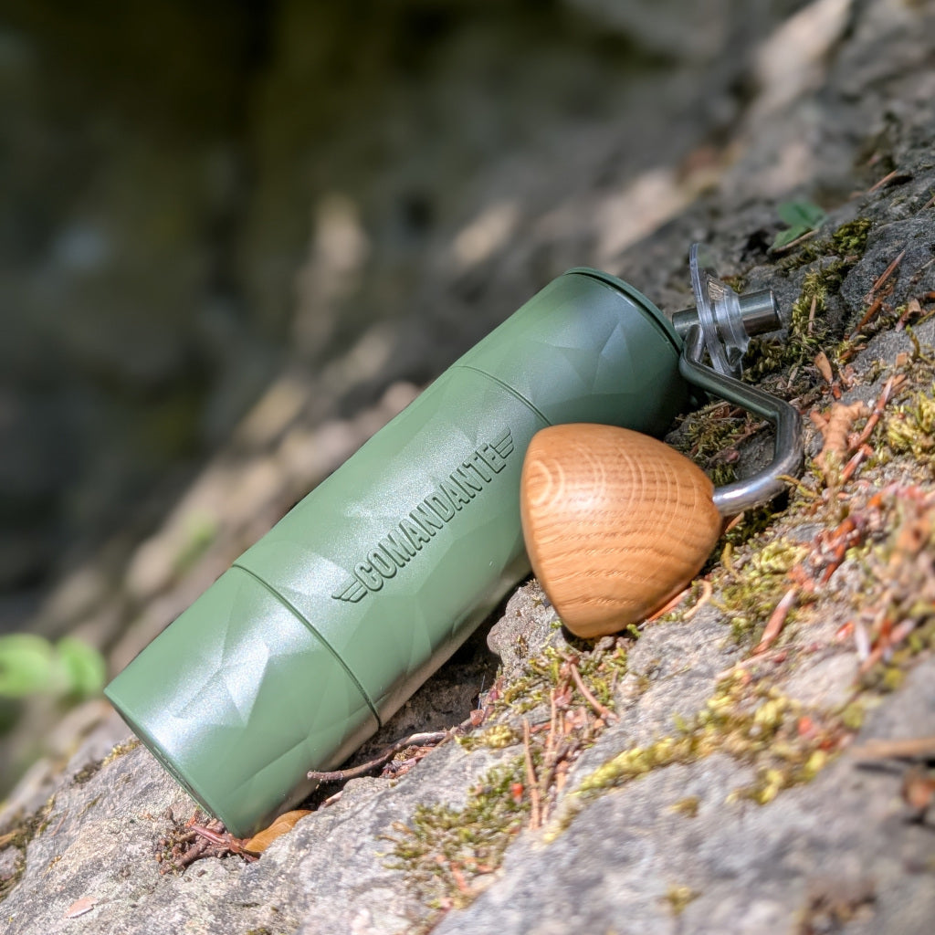 Das Bild zeigt eine Comandante Trailmaster X25 Forest mit Kurbel, welche auf einer Steinoberfläche liegt und von der Sonne angestrahlt wird. Der Hintergrund lässt unscharf eine Felsformation erkennen.