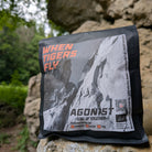 Das Bild zeigt eine schwarze Kaffeeverpackung mit dem grau, orangenen Etikett von WHEN TIGERS FLY auf einem Felsvorsprung stehend. Im Hintergrund sind unscharf Felsen und Wald zu erkennen. 
